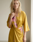 Robe satinée jaune à fleurs roses vue en buste, avec détail sur le col V et les manches larges