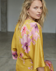 Vue rapprochée du dos d'une robe midi satinée imprimée fleurs roses sur fond jaune