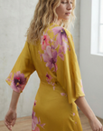 Détail du dos d'une robe midi satinée jaune avec imprimé floral rose et manches larges