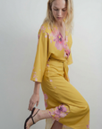 Vue de côté d'une robe midi satinée jaune à motifs floraux roses, col V et manches larges