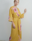 Vue de trois-quarts d'une robe midi croisée satinée jaune imprimée de fleurs roses