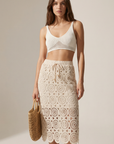 Femme dans une jupe en dentelle crème en coton taille haute élégante, ajoutant une touche féminine à son look décontracté.