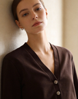 Portrait d'une femme portant un ensemble deux pièces coton femme en marron, mettant en avant la veste à col V et les détails des boutons.
