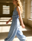 Modèle portant un pantalon court plissé taille haute ceinture élastique à poches, déambulant dans un environnement lumineux, parfait pour un look décontracté. Pantalon plissé femme.