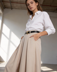 Gros plan sur une femme en pantalon fluide taille haute femme, avec des poches, en pose chic, mettant en valeur sa silhouette moderne.
