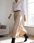 Femme portant un pantalon fluide taille haute femme, stylistiquement élégant avec une chemise blanche, jambe large, lors d'une promenade à l'intérieur.