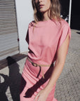 Femme marchant avec assurance en robe midi satinée avec ceinture fine couleur rose, montrant un style contemporain.