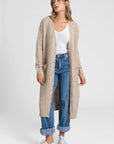 Femme avec un cardigan long femme beige, en laine mélangée, mettant en avant un look décontracté et chic, idéal pour la saison.
