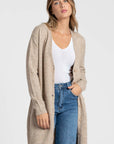 Détail d'un cardigan long femme beige, soulignant les boutons et poches, une pièce polyvalente pour toute garde-robe.