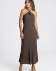 Modèle portant une robe midi halter fluide en viscose marron, parfaite pour l'été avec des sandales compensées.