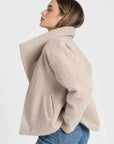 Profil d'une femme avec un look chic dans une veste courte effet poil doublée col à revers, parfait pour les saisons intermédiaires. Veste courte femme.