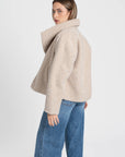 Vue arrière d'une femme avec une veste courte effet poil doublée col à revers beige, idéale pour compléter une tenue décontractée. Veste courte femme.