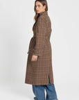 Manteau long femme en coton coupe ceinturée, vue arrière d'une femme le portant, révélant le drapé et la ceinture dans le dos.