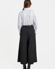 Vue arrière d'une femme en pantalon fluide taille haute femme noir, soulignant le style et la coupe moderne.