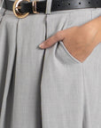 Focus sur le pantalon fluide taille haute femme gris, montrant une main dans la poche avec une ceinture décorative.