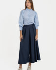 Femme avec pantalon fluide taille haute femme bleu marine, posant en regardant l'objectif, style contemporain.