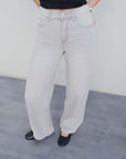 Zoom sur un jean large gris taille mi-haute, mettant en valeur sa coupe moderne et ses poches avant.