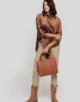 Femme portant un pantalon fluide taille haute en viscose stretch, avec un haut brun et un sac marron, dans un style élégant.