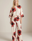 Pantalón de mujer con estampado floral rojo sobre blanco: corte recto moderno, tejido ligero y comodidad óptima.