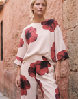 Pantalón de mujer con estampado floral rojo sobre blanco: corte recto moderno, tejido ligero y comodidad óptima.
