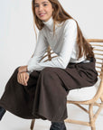 Femme assise sur une chaise avec un pantalon large taille haute femme, combiné avec un haut blanc, montrant un style élégant et décontracté.