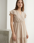 Robe fluide manches courtes en polyester légère — coupe féminine, modèle beige, posée de façon stylée.