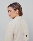 Vue arrière d'un modèle avec un trench coat court femme beige à double boutonnage, mettant en avant le style et la sophistication de la coupe.