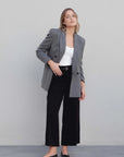 Modèle portant un blazer femme chic gris à rayures fines avec un pantalon noir, illustrant le style moderne et élégant.