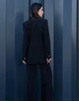 Vue arrière d'un modèle portant le Blazer Femme Noir à Boutons Argentés, montrant la coupe élégante et contemporaine du blazer chic femme.