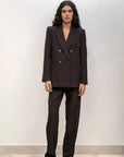 Femme debout avec un blazer double boutonnage femme oversize et un pantalon assorti, montrant une allure moderne et élégante.