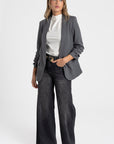 Modèle portant un blazer femme chic élégant avec manches froncées, associé à un pantalon large, parfait pour un look décontracté.