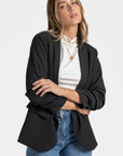 Profil d'un modèle en blazer femme chic noir, affichant la tendance avec des manches froncées.