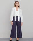 Alt texte d’une blouse fluide élégante blanche à nouer avec pantalon large bleu foncé