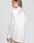 Vue arrière d'une blouse satinée femme élégante blanche, mettant en avant le col chemise et le drapé sur un modèle.