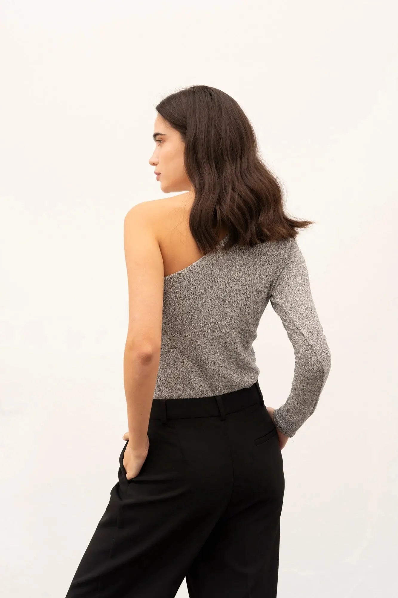 Vue côté d'une femme en body asymétrique, soulignant le design asymétrique et le confort de la pièce.