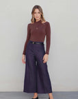 Femme posant en body drapé chic – Manches longues – Marron – Col croisé, stylisé avec un pantalon large, illustrant la polyvalence du body manche longue femme.