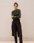 Look chic avec le body vert olive asymétrique et un pantalon noir, mannequin en pose.