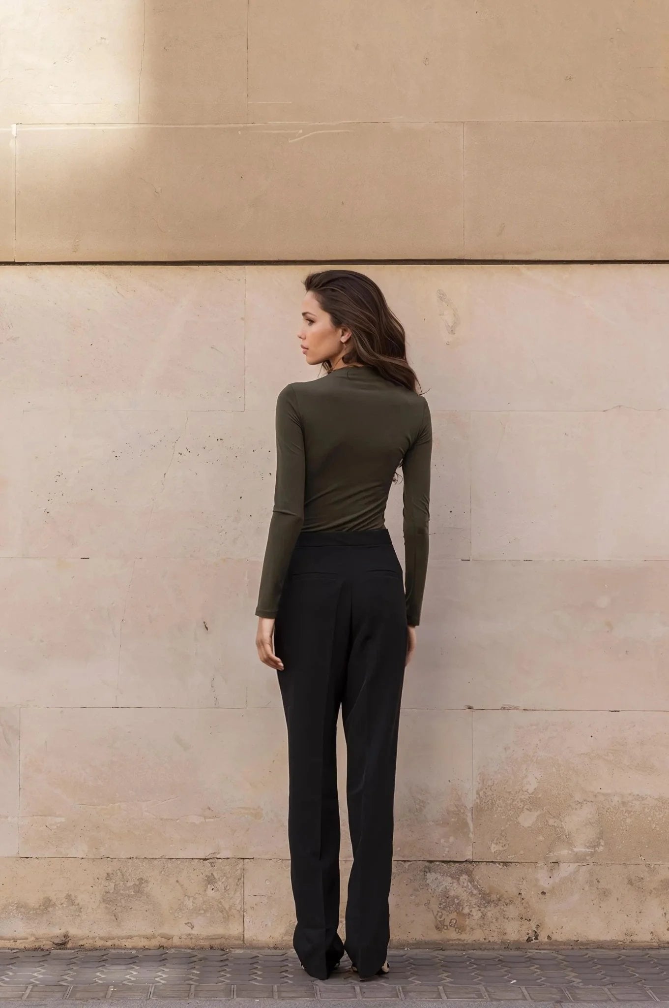 Femme portant un body drapé vert asymétrique manches longues et pantalon noir