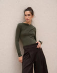 Body vert olive asymétrique avec drapé élégant, manches longues, porté par un modèle avec un pantalon large.