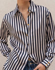 Gros plan sur une chemise rayée bleu marine et blanc pour femme, mettant en avant les boutons dorés ajoutant une touche élégante. Un incontournable dans la mode avec la chemise rayée femme.