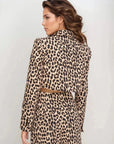 Femme vue de dos en veste blazer leopard femme, style unique avec imprimé animal, devant un fond clair.