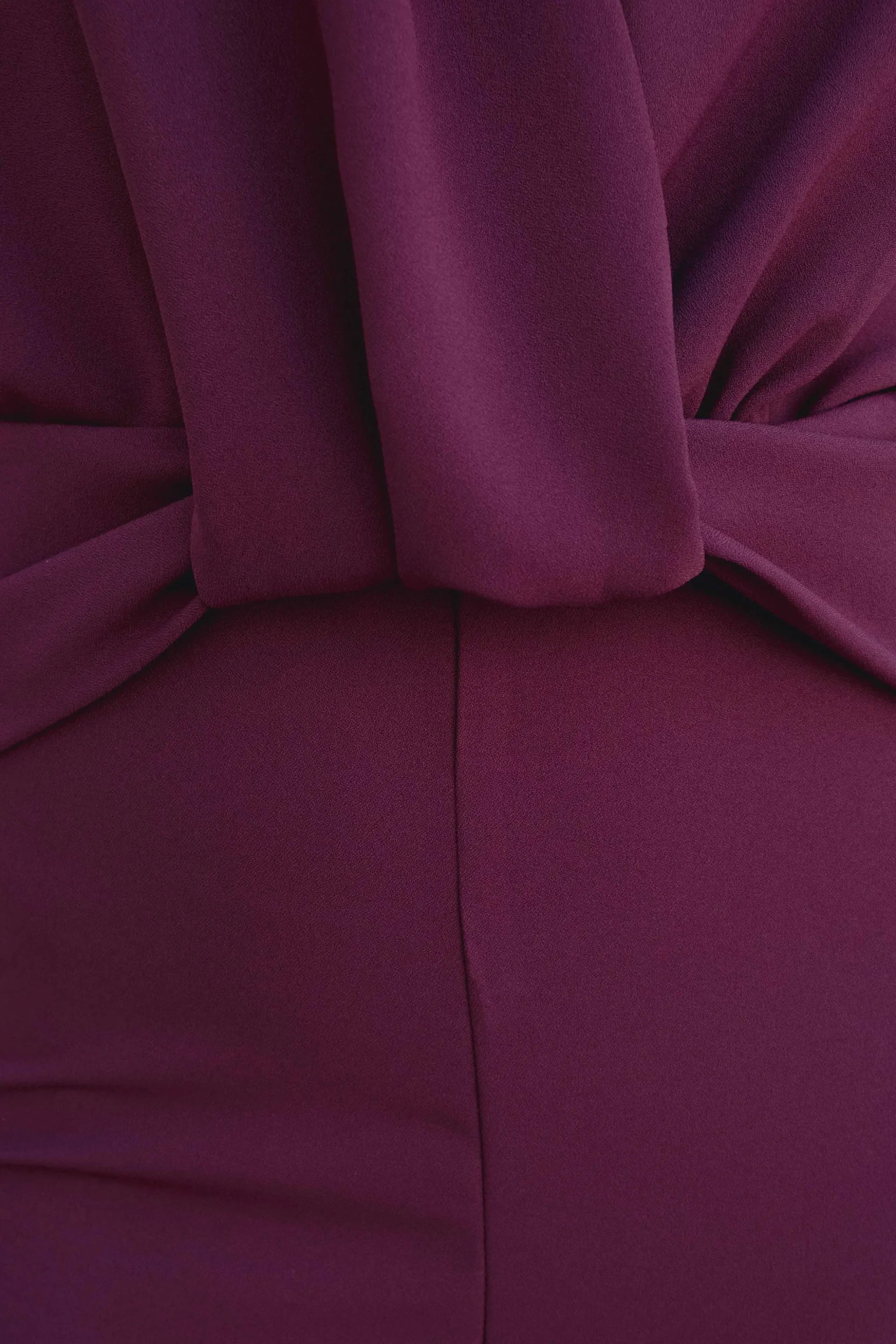 Photo d’une combinaison pantalon bordeaux prune chic avec tissu foncé et détail noué à la taille