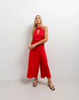 Femme en pose avec un pantalon jupe femme rouge éclatant taille haute, ajoutant une touche chic à son look pour une soirée.