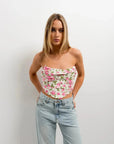 Modèle affichant le Top Bustier Fleuri À Roses Inspiré Du Corset, offrant une allure raffinée et féminine tout en portant un jean.