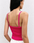 Vue arrière d'une femme avec un pull crop top fuchsia en maille côtelée, mettant en avant les fines bretelles et le confort du vêtement.