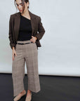 Femme portant un Pantalon culotte à carreaux marron, associé à un blazer et un top noir, offrant un look moderne et sophistiqué.