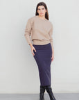 Femme affichant une jupe midi marine taille haute avec un pull beige, capturant le style décontracté de la jupe midi.