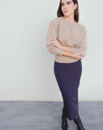 Modèle portant une jupe midi marine taille haute avec un pull beige, mettant en valeur la jupe midi dans un cadre moderne.