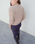 Vue arrière d'un modèle en jupe midi marine taille haute, associée à un pull beige, soulignant la coupe élégante de la jupe midi.