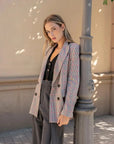 Modèle avec le blazer femme double boutonnage à carreaux de Sapiato, stylé avec un pantalon gris élégant.